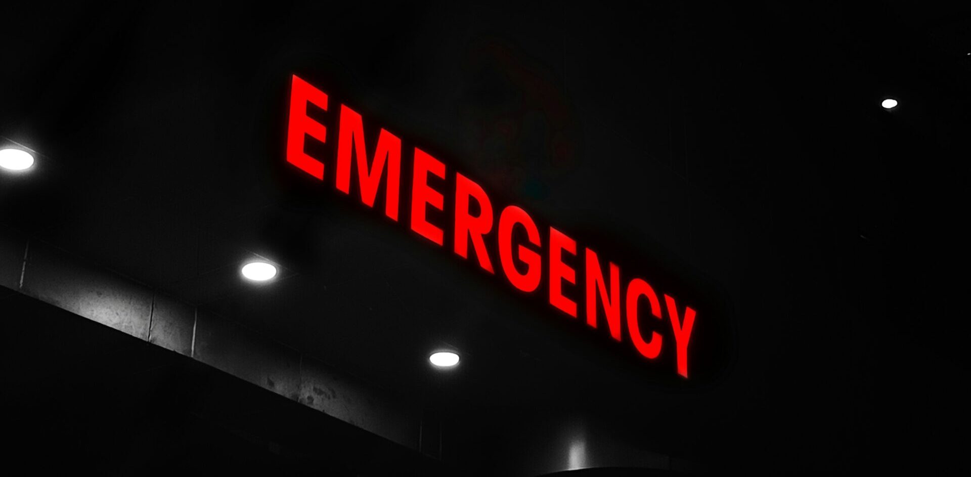 Ein leuchtend rotes "Emergency"-Schild erhellt die dunkle Nacht, symbolisch für die schnelle Reaktion von BlueBranch GmbH.